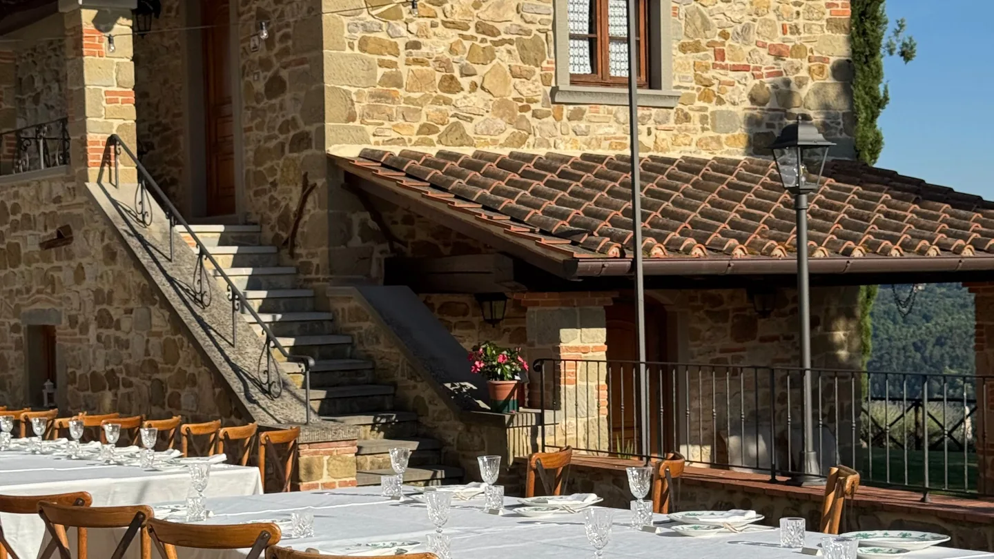 A long table laid outside a stone villa, set for a party
